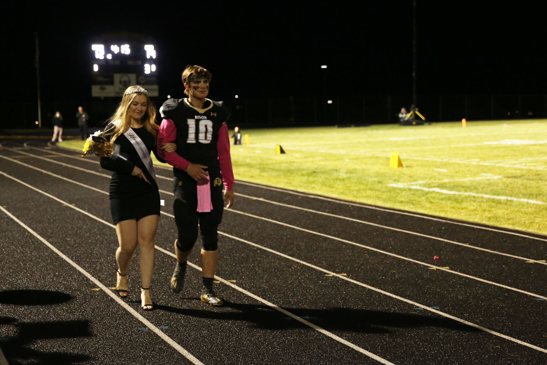 Cassie Downare and Jackson Moon walk arm in arm to the center of the track